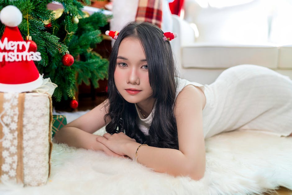 A young woman relaxing indoors by a Christmas tree, embodying holiday spirit with festive decor.