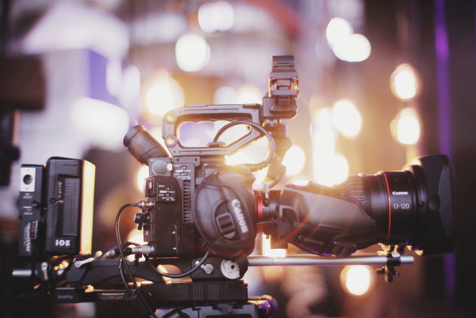 Close-up of professional video camera setup for studio filming with blurred lights in the