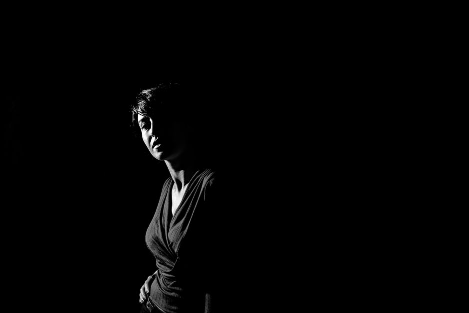 Moody black and white portrait highlighting dramatic shadow on a woman's face.
