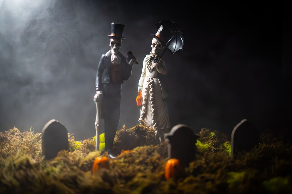 Mysterious skeleton figures in Victorian attire amidst gravestones, perfect for Halloween themes.