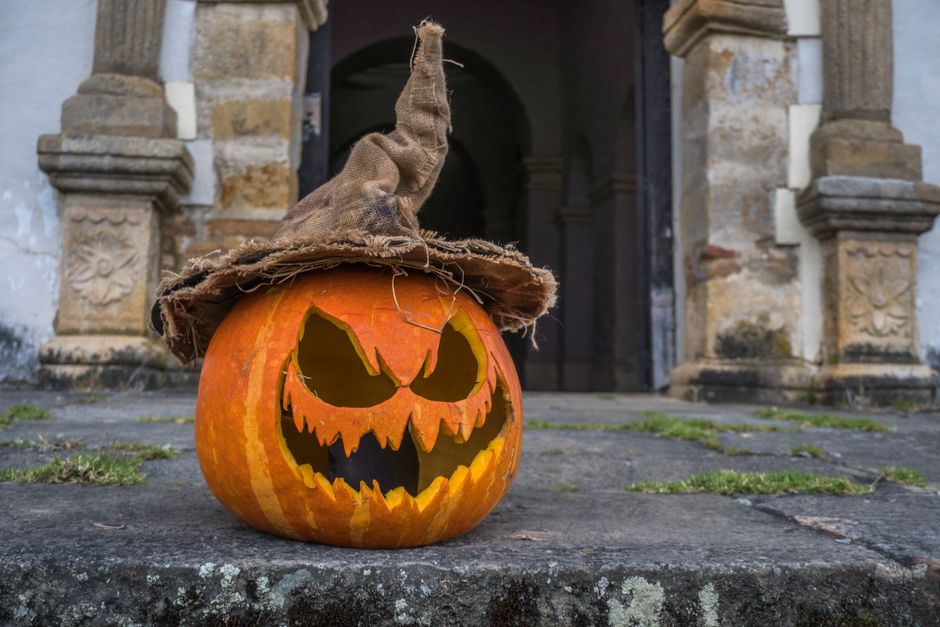 A scary jack-o'-lantern with a witch hat on a historic stone doorway in Guasca, Colombia.
