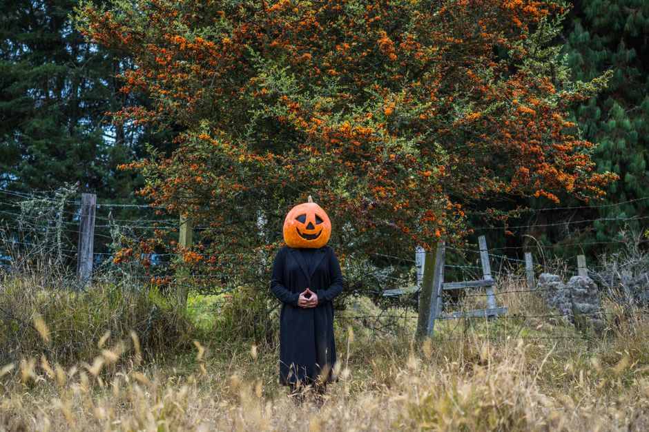 Spooky pumpkin-head figure in dark attire amid autumn foliage in Guasca, Colombia.