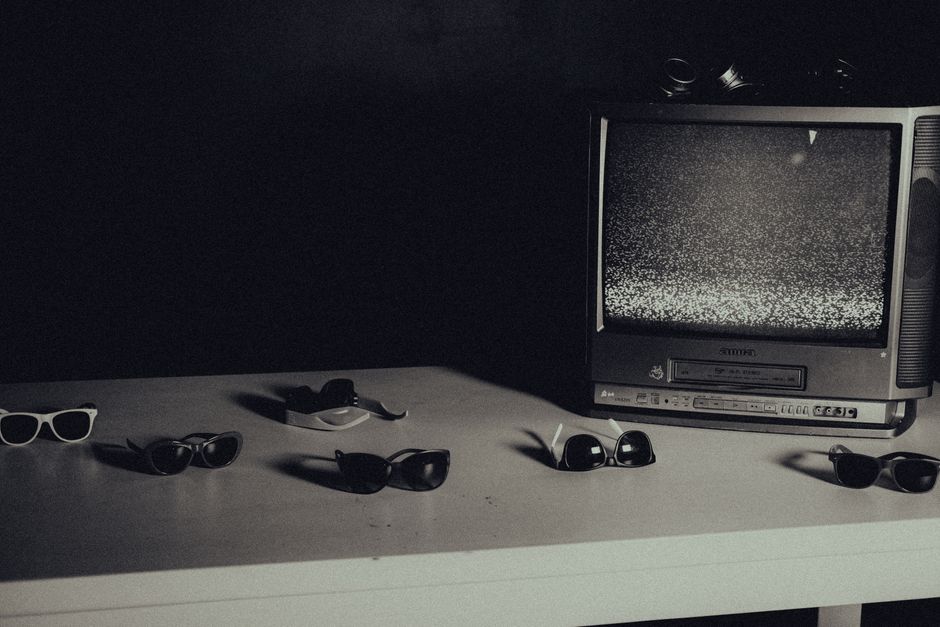 Retro styled still life with vintage TV showing static and multiple sunglasses on a white 