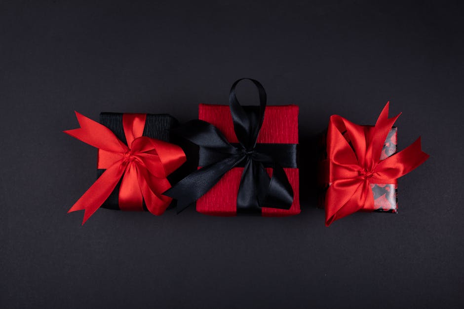 Flat lay of stylish gift boxes wrapped in black and red with elegant ribbons, perfect for celebrations.