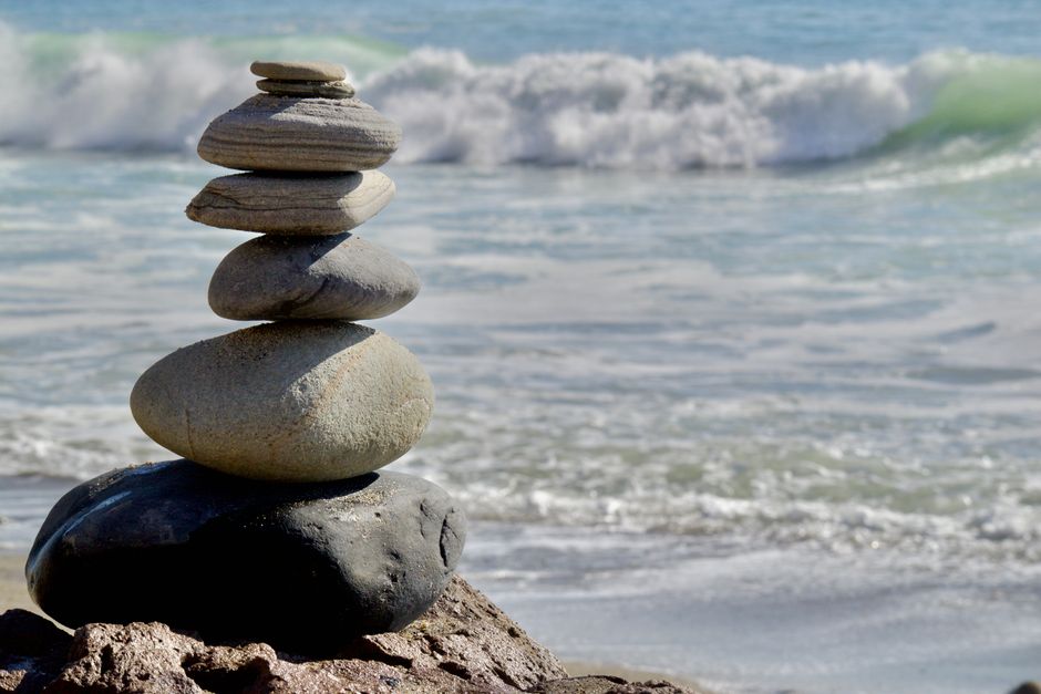 A harmonious stack of stones by the seashore, with ocean waves in the background.
